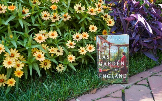 A book titled "The Last Garden in England" propped up in a flower garden bed.